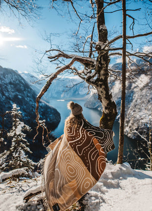 A person standing on a snowy hill, wrapped in a cozy blanket.