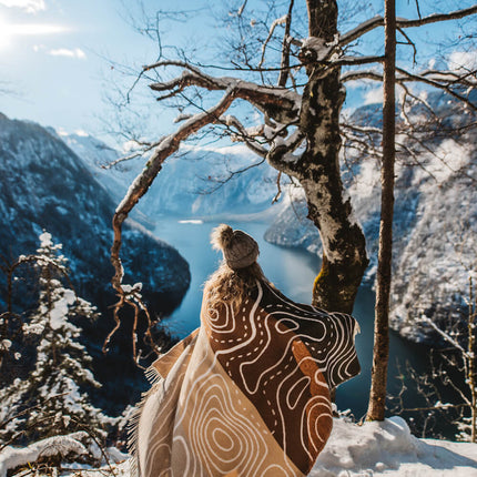 A person standing on a snowy hill, wrapped in a cozy blanket.